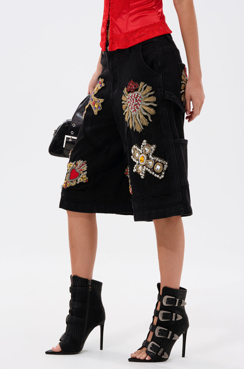A person wearing WILD AND FREE DENIM SHORTS, a red corset top, black open-toe high-heeled booties with multiple buckles, and holding a black handbag.