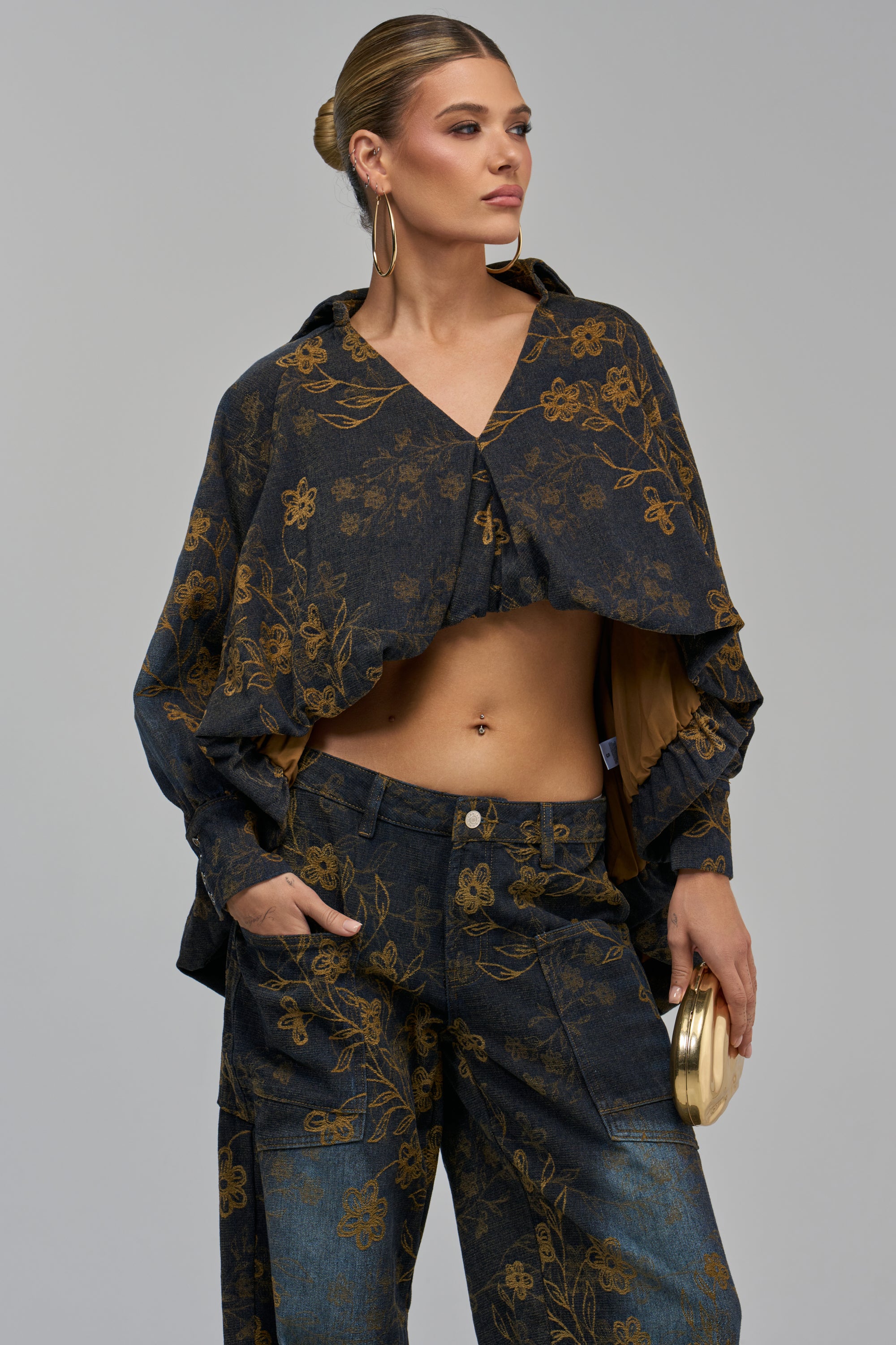 A person wears a cropped, dark denim GET IT RIGHT DENIM BLOUSE with a tan floral pattern and matching trousers, holding a gold clutch.