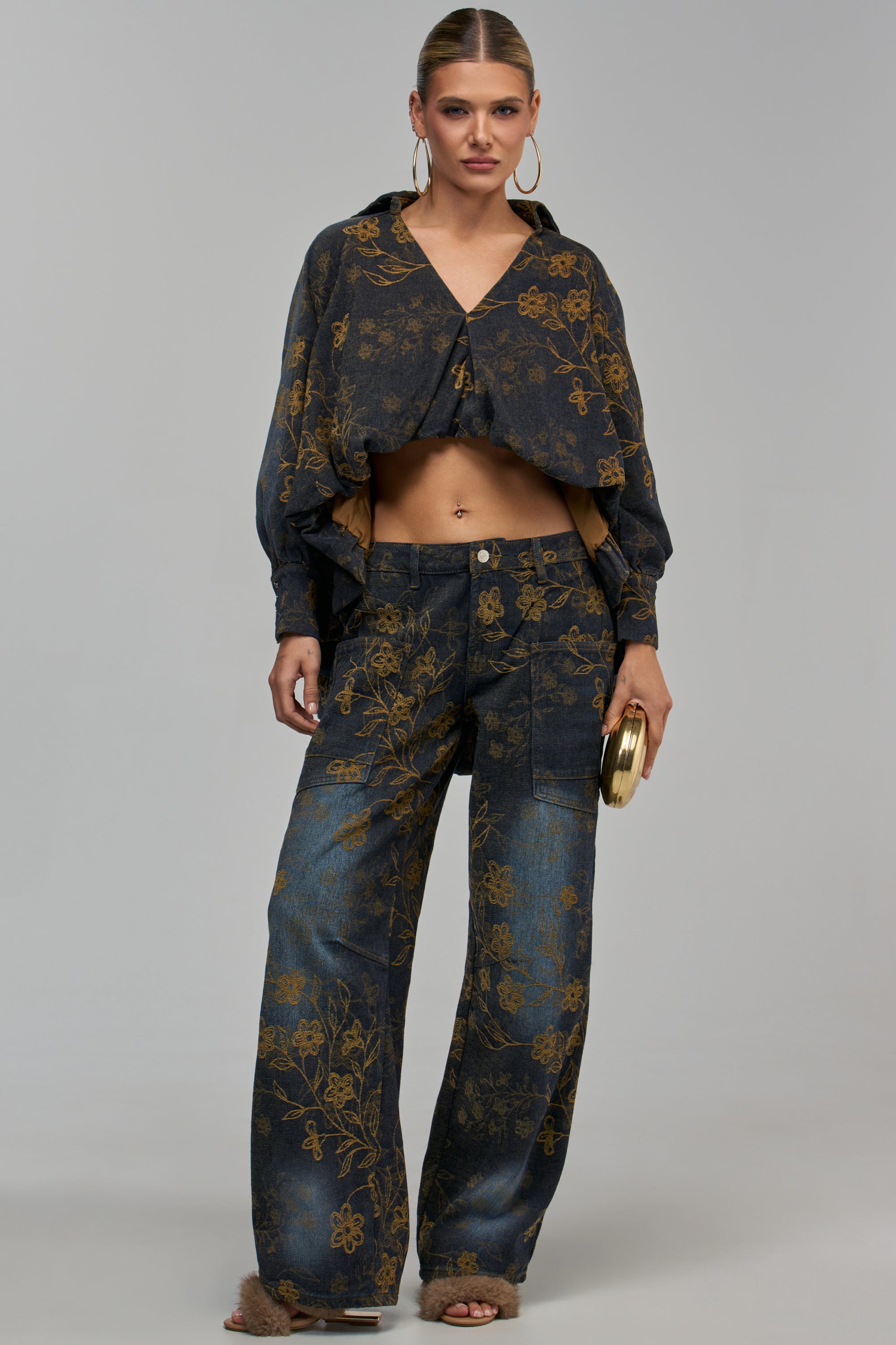 A model wears the GET IT RIGHT FLORAL DENIM, featuring a cropped, long-sleeved button-down shirt and matching wide-leg jeans in dark blue denim with a gold floral pattern.