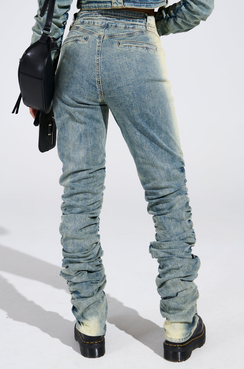 A person wearing UP ALL NIGHT DENIM PANT and a matching long-sleeve top, holding a black handbag. They stand confidently in black platform shoes against a plain white background.