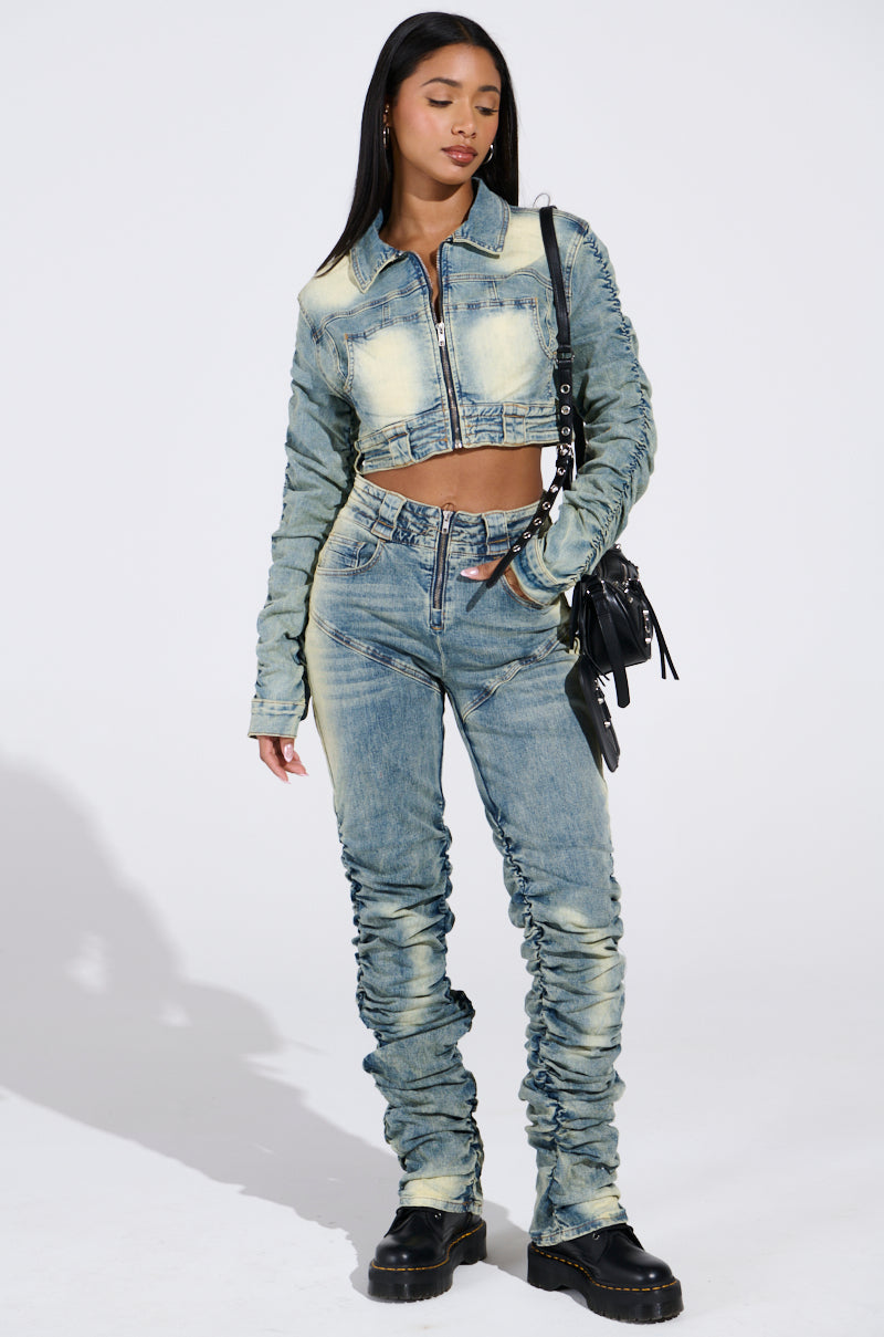 Modeling a stylish outfit, a person wears the "UP ALL NIGHT DENIM PANT" with a matching stretchy denim cropped jacket. They carry a black shoulder bag and sport black platform shoes against a plain white background.