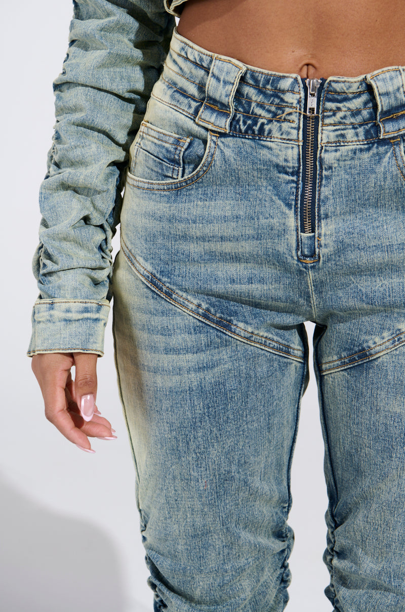 Someone in light blue high-rise UP ALL NIGHT DENIM PANT with a zipper and button, matched with a long-sleeve denim top, enjoys comfort from the stretchy fabric, as their left hand rests by their side.