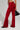 A person wearing the MEET ME HALF WAY TROUSER with a flared silhouette and black high-heeled boots is holding a black handbag. The background is plain and light-colored.