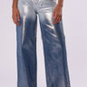 A person wearing high-rise waist, wide-leg LITTLE MISS SUNSHINE DENIM PANT in metallic silver, paired with white sneakers. The pants boast a metallic sheen denim look, blending a shiny texture with a denim-blue color. The background is plain white.