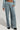 Wearing the FREYA SWEATPANTS in a light blue corduroy finish, featuring a loose fit and an elastic waistband, someone has their right hand tucked into one of the pockets. The sweatpants are stylishly combined with black shoes against a simple, light-colored background.