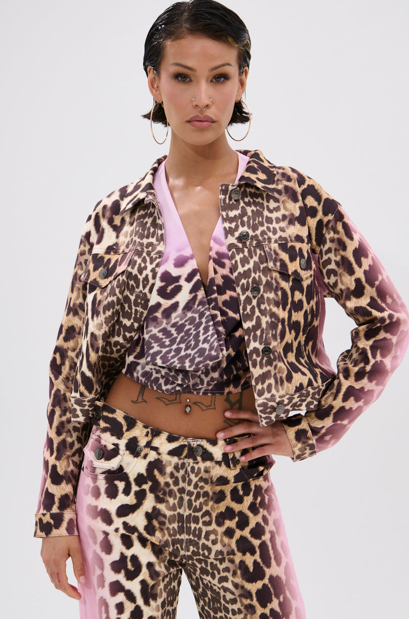 A woman poses confidently in the COCO LEOPARD PRINT DENIM JACKET featuring a pink ombre design, styled with matching pants, wet-look hair, hoop earrings, and subtle natural makeup.