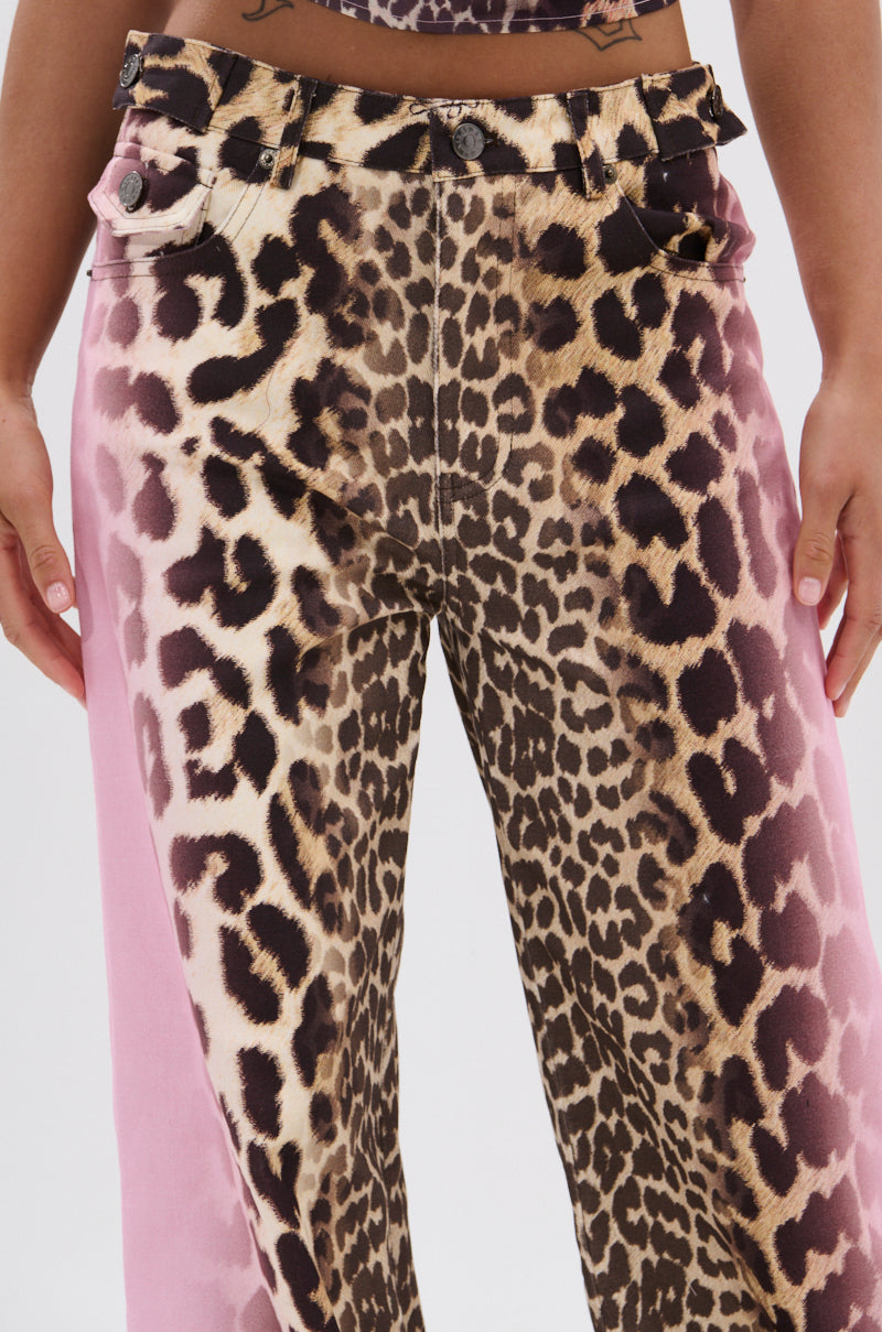 Close-up of a person wearing COCO LEOPARD PRINT DENIM high-waisted pants, showcasing a bold leopard print front and pink side panels, with their hands relaxed at their sides.