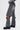 Wearing JACQUELINE CUTOUT DENIM PANTS—vintage-washed gray denim with unique detachable knee sections, visible seams, high-rise fit, back pocket graphic—and chunky black boots, exposing skin above the knees.