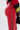 A close-up of a person wearing SEXY FAUX LEATHER RED LACE-UP PANTS with side lace-up detail, paired with a black and red top featuring yellow stripes and holding a small black bag.