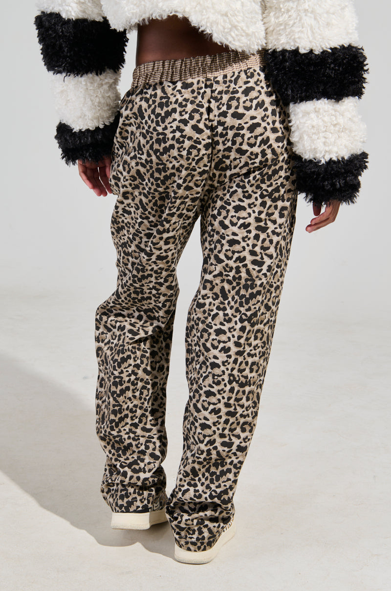 A person wearing the KISS ME CHEETAH PANT, featuring a wide leg silhouette, pairs it with a fluffy black-and-white striped jacket while standing with their back to the camera to showcase the pattern against a plain white background.