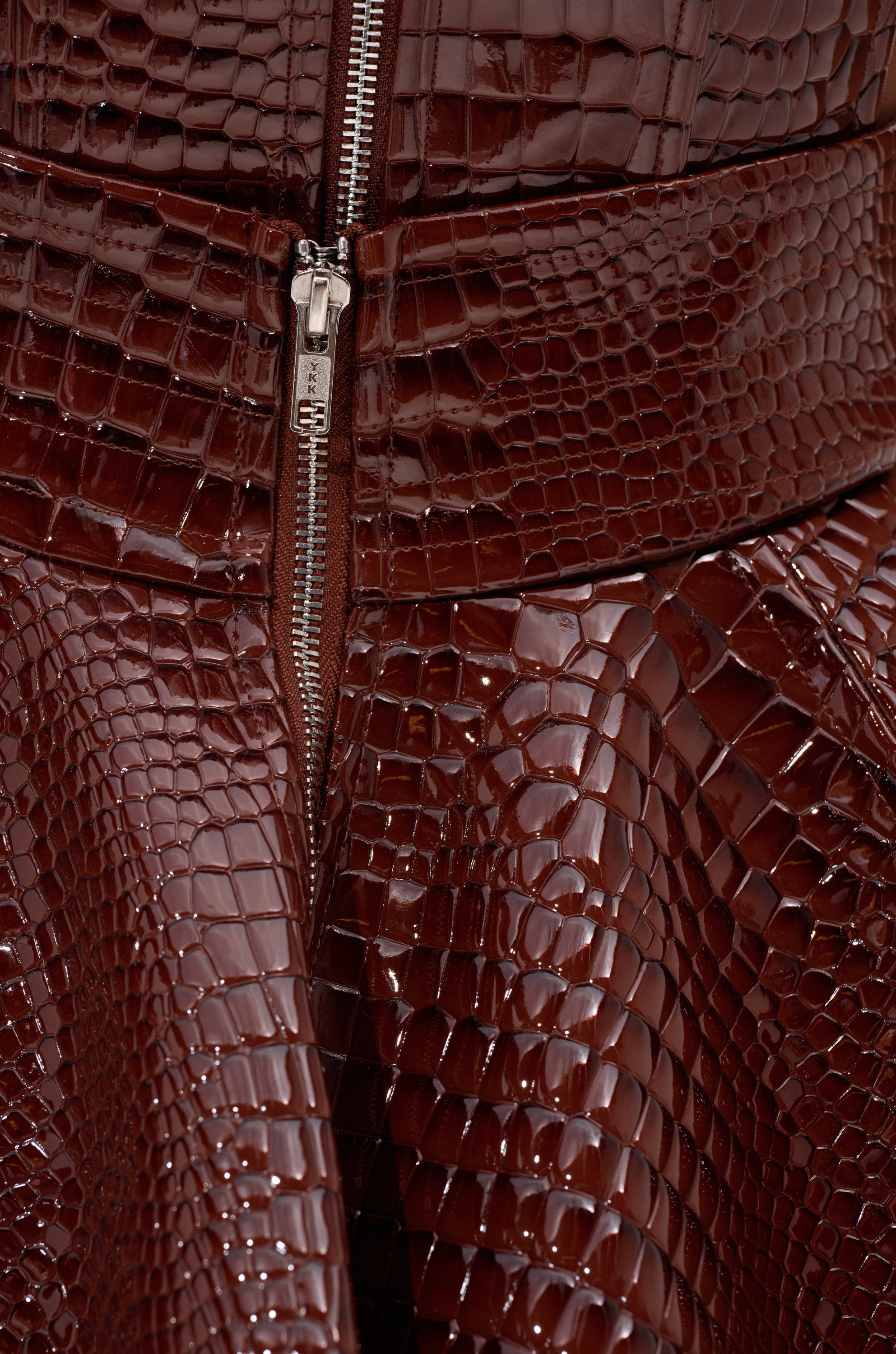 A close-up of the TOO GOOD FOR YOU CROCODILE MINI SKIRT, a high-rise mini skirt crafted in glossy faux patent leather.