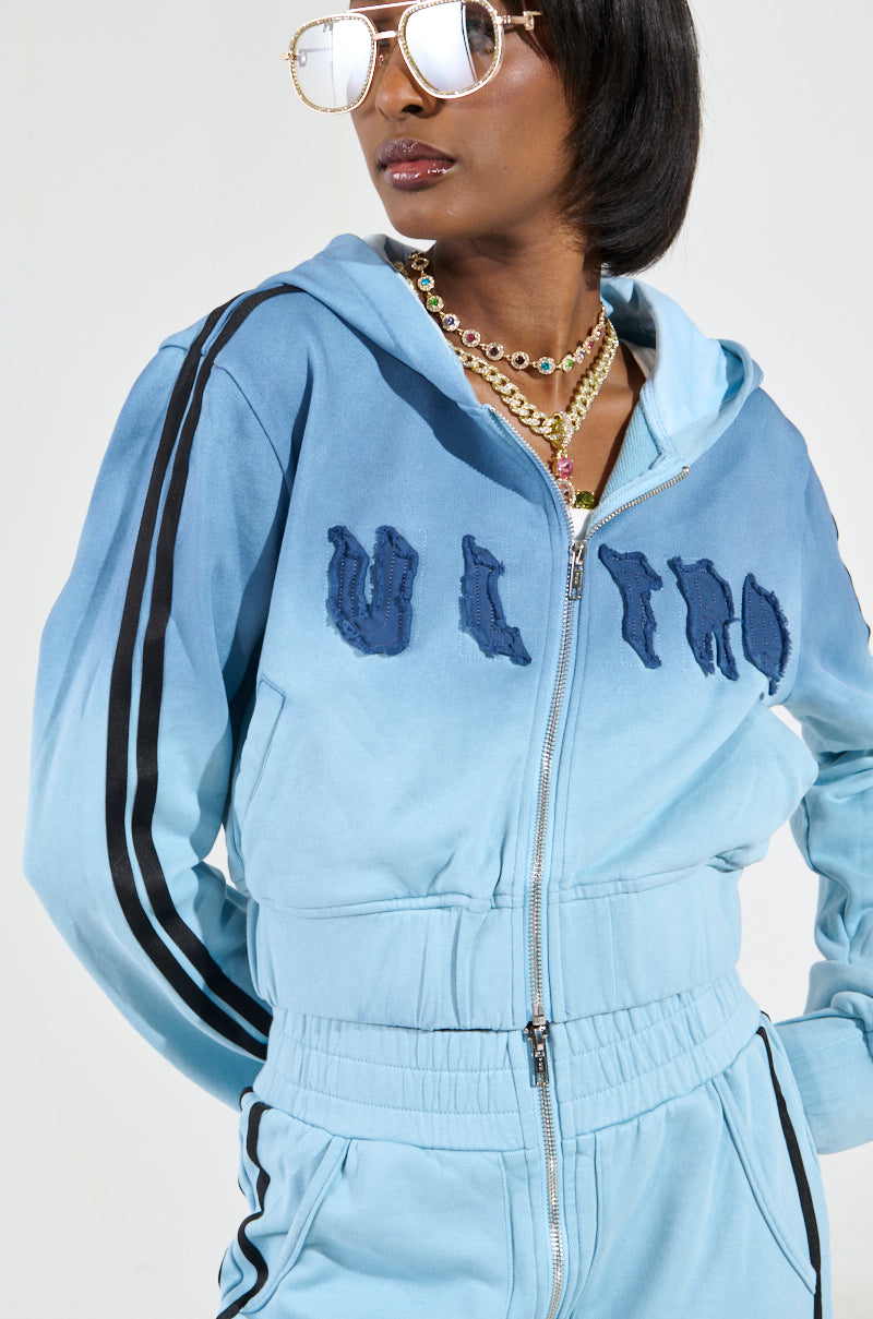 A person wearing reflective sunglasses and a gradient blue DON'T TALK TO ME I'M RUNNING ERRANDS ZIP UP SWEATSHIRT with "ULTRA" text, which incorporates ombré styling. They are accessorized with layered gold necklaces and a hood, standing against a neutral background.