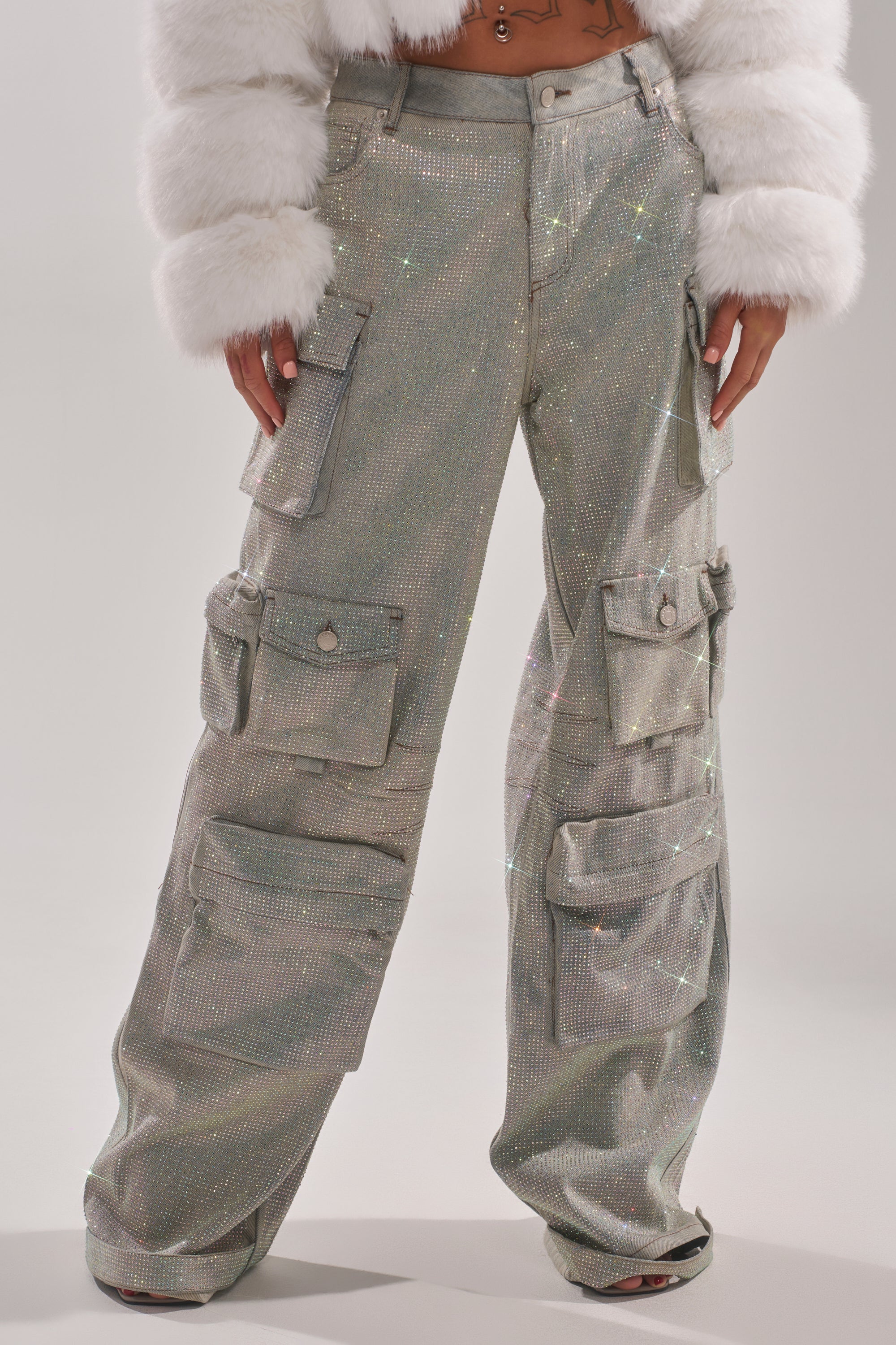 A person wearing the BLING BLING CARGO DENIM pants with multiple pockets and a cropped white faux fur jacket stands against a plain light background. 1