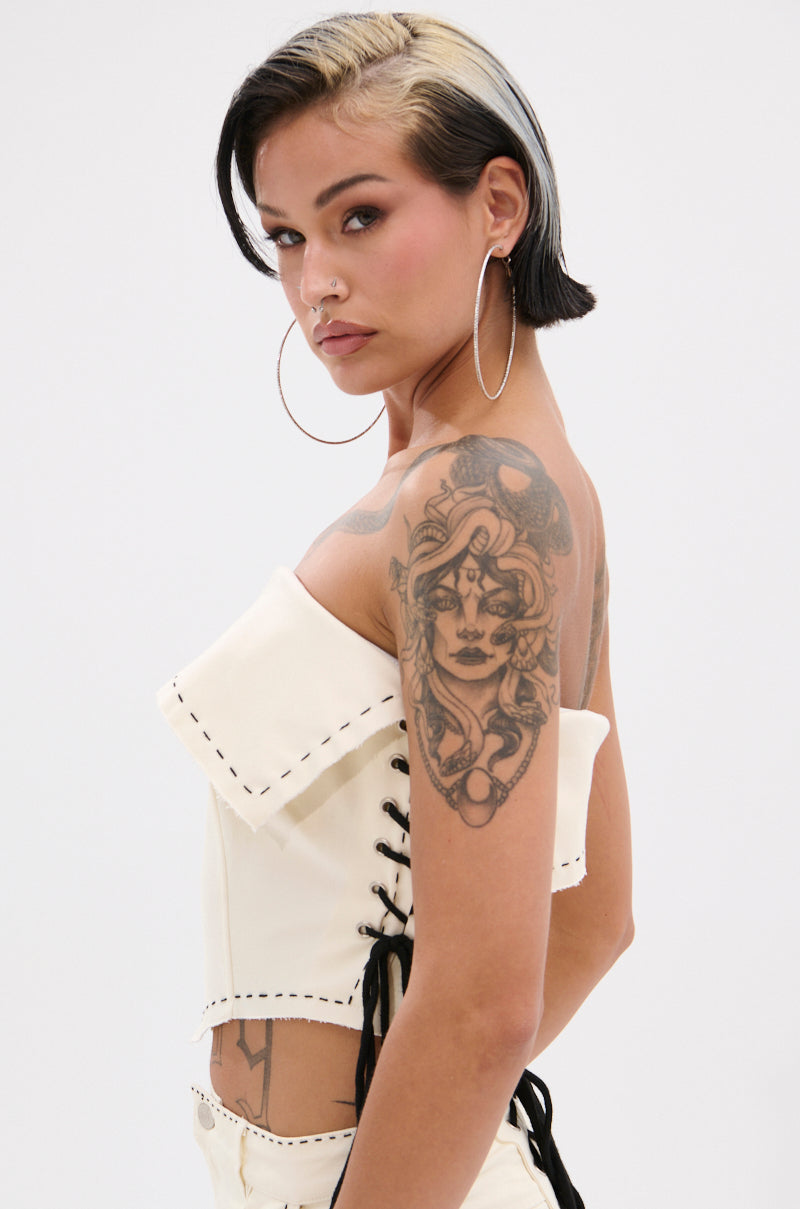 A woman with short dark hair and a blonde streak poses confidently in the BREAK MY LOVE LINEN TUBE TOP, accessorized with large hoop earrings, a nose ring, and a detailed woman's face tattoo on her upper arm. 4