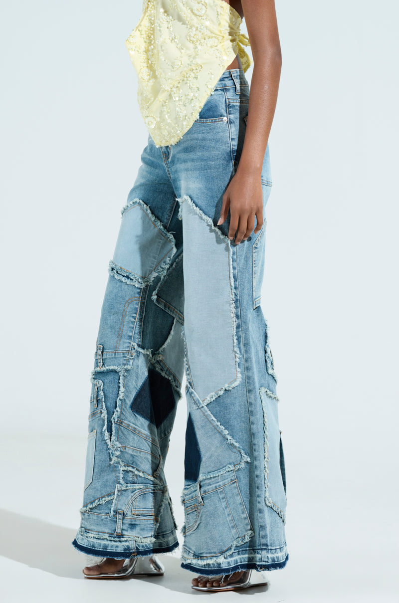 Wearing ALL OVER ME DENIM PATCHWORK JEANS in a flared silhouette, they flaunt various shades of blue with frayed edges. These high-rise jeans are styled perfectly with a light yellow, textured top and clear-heeled shoes.