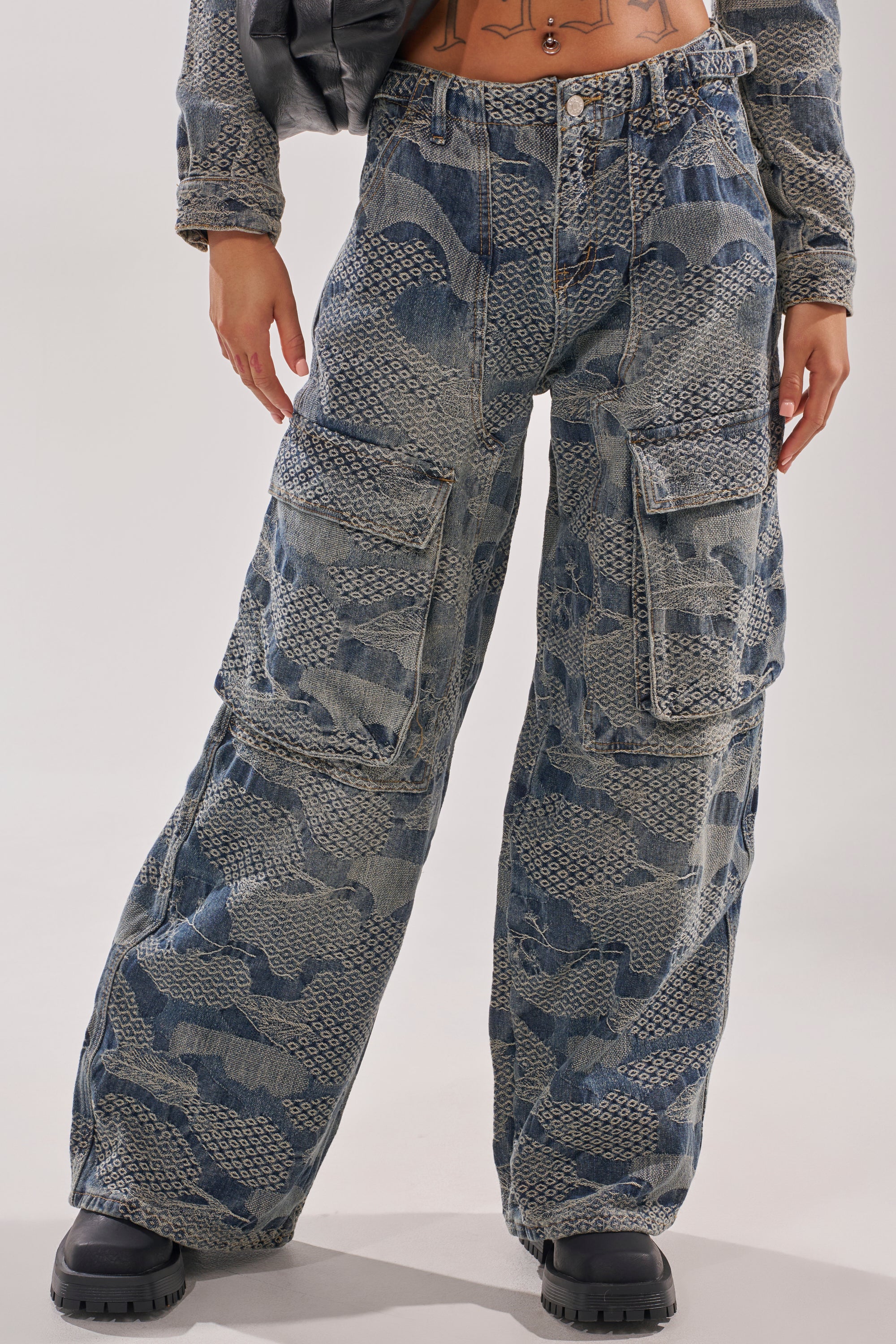 Model showcases only the lower body in the I THINK YOU WANNA KNOW DENIM CARGO PANT—loose-fitting, wide-leg blue denim with oversized pockets—styled with a matching long-sleeve top and black chunky boots against a plain background. 4