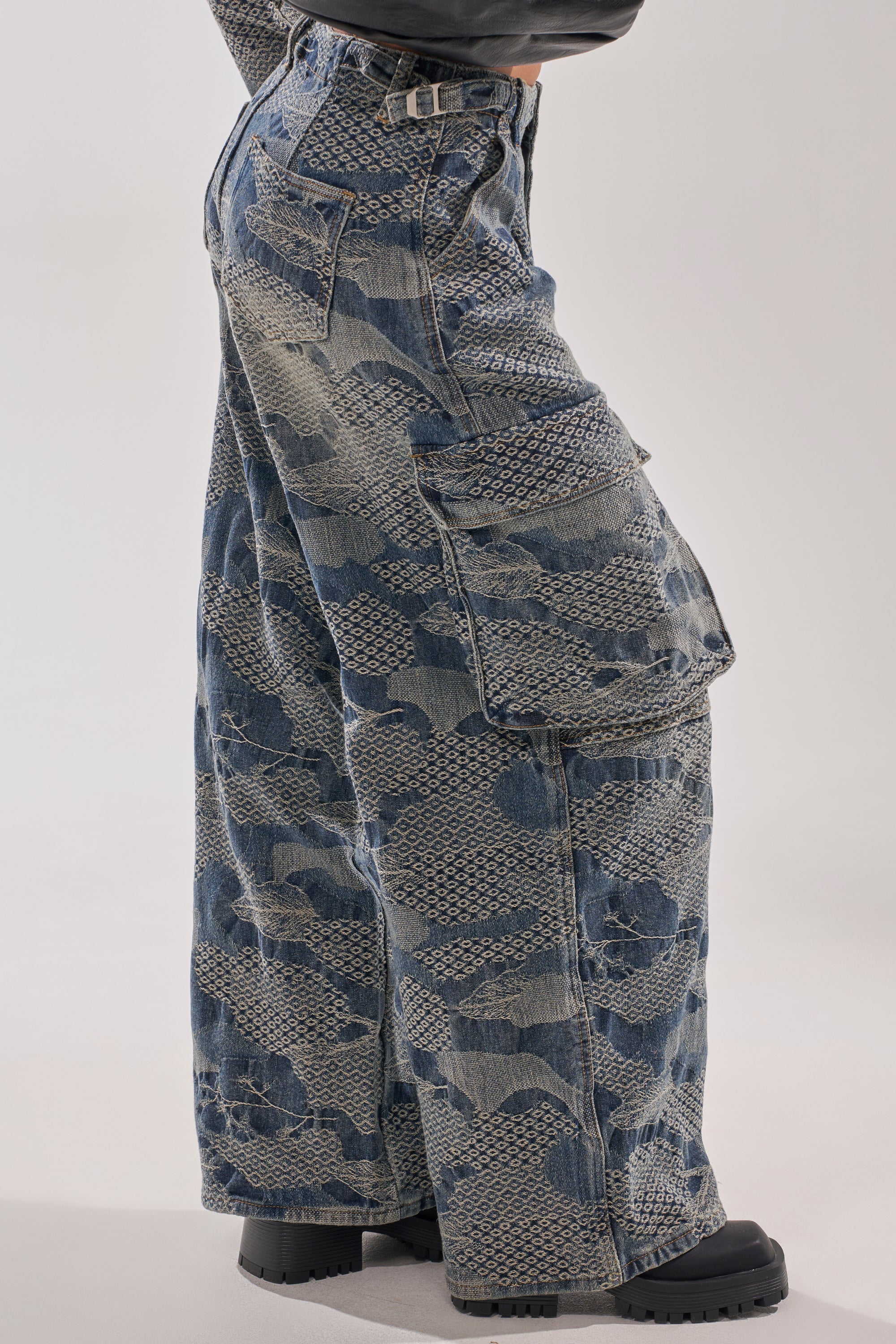 A person wears the I THINK YOU WANNA KNOW DENIM CARGO PANT, featuring wide legs, patchwork lace denim details, and side pockets with chunky black boots. Only their lower body is visible against a plain background. 6