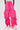 Model wears GIRL ON FIRE RUCHED JOGGER in bright pink with wide-leg and drawstring details, paired with white sneakers, standing against a plain light background.