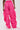 Someone stands facing away in the GIRL ON FIRE RUCHED JOGGER—bright pink, high-waisted jogger pants with an elastic waistband and ankle drawstrings—creating a bold streetwear look against a plain light gray background.