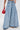 Wearing THE BEST ONE YET WIDE LEG DENIM—vintage-inspired, high-rise, light blue wide-leg jeans with front pleats—paired with a small red chain-detailed handbag. Only the lower torso and legs are shown.