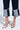 A person wearing LOCKED UP DENIM BERMUDA SHORTS with exposed light denim lining and pointed-toe high heels featuring a beige and brown spotted pattern with metallic gold tips.