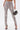 A person wearing the IN THE SUN SNAKE LACE-UP PANT with a gray snakeskin pattern and front ankle slits, paired with black high-heeled sandals and carrying a small black handbag featuring chain and lock details.