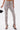 A person wearing IN THE SUN SNAKE LACE-UP PANT—a high-rise, lace-up, snakeskin-print pant with front ankle slits—black heeled sandals, and holding a small black chain-strap handbag. The background is plain white.