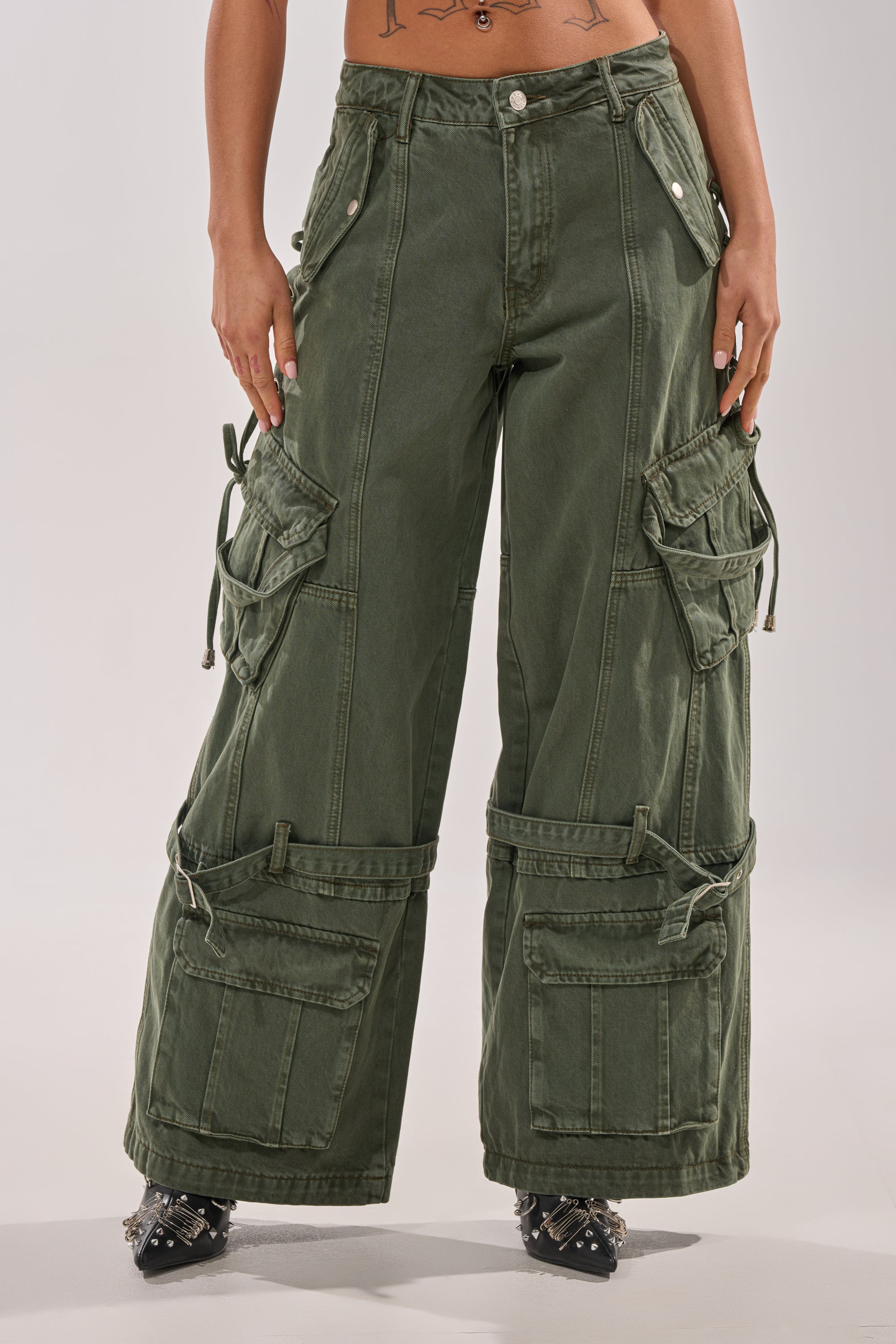 Wearing KARA CARGO DENIM—high-waisted, wide leg olive green cargo pants with multiple large pockets and silver snap buttons—paired with pointed black shoes; only the lower torso and legs are shown. 2