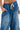 Someone models the DONT MESS WITH ME DENIM JOGGER—loose-fitting blue joggers with large front pockets and a white drawstring, styled with a partially visible bare midriff for a cool streetwear look.