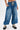 Model wears the DONT MESS WITH ME DENIM JOGGER—high-rise blue denim cargo joggers with large front pockets and a white drawstring—styled with chunky black streetwear shoes with beige laces, standing against a plain white background.