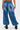 Model wearing the DONT MESS WITH ME DENIM JOGGER—high-rise, wide-leg blue jeans with large back pockets—paired with black chunky boots, standing back to camera against a light background for a streetwear vibe.