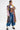 A person poses confidently in the DONT MESS WITH ME DENIM JOGGER, styled with a colorful patchwork plaid coat, white cropped tank top, and chunky white lace-up boots, exuding streetwear flair against a plain white background.
