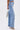 Someone wearing the FEELING GRATEFUL RHINESTONE RELAXED DENIM—a high-waisted, wide-leg jean with rhinestone embellishments—paired with silver high-heeled sandals and a small silver handbag against a plain white background.