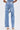 A person shown from the back wears FEELING GRATEFUL RHINESTONE RELAXED DENIM with pearl embellishments on the sides and back pockets, styled with heeled sandals and a studded denim top.