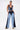 A woman in a blue and white outfit featuring the FIRST CLASS RELAXED DENIM PANT with a wide-leg silhouette.