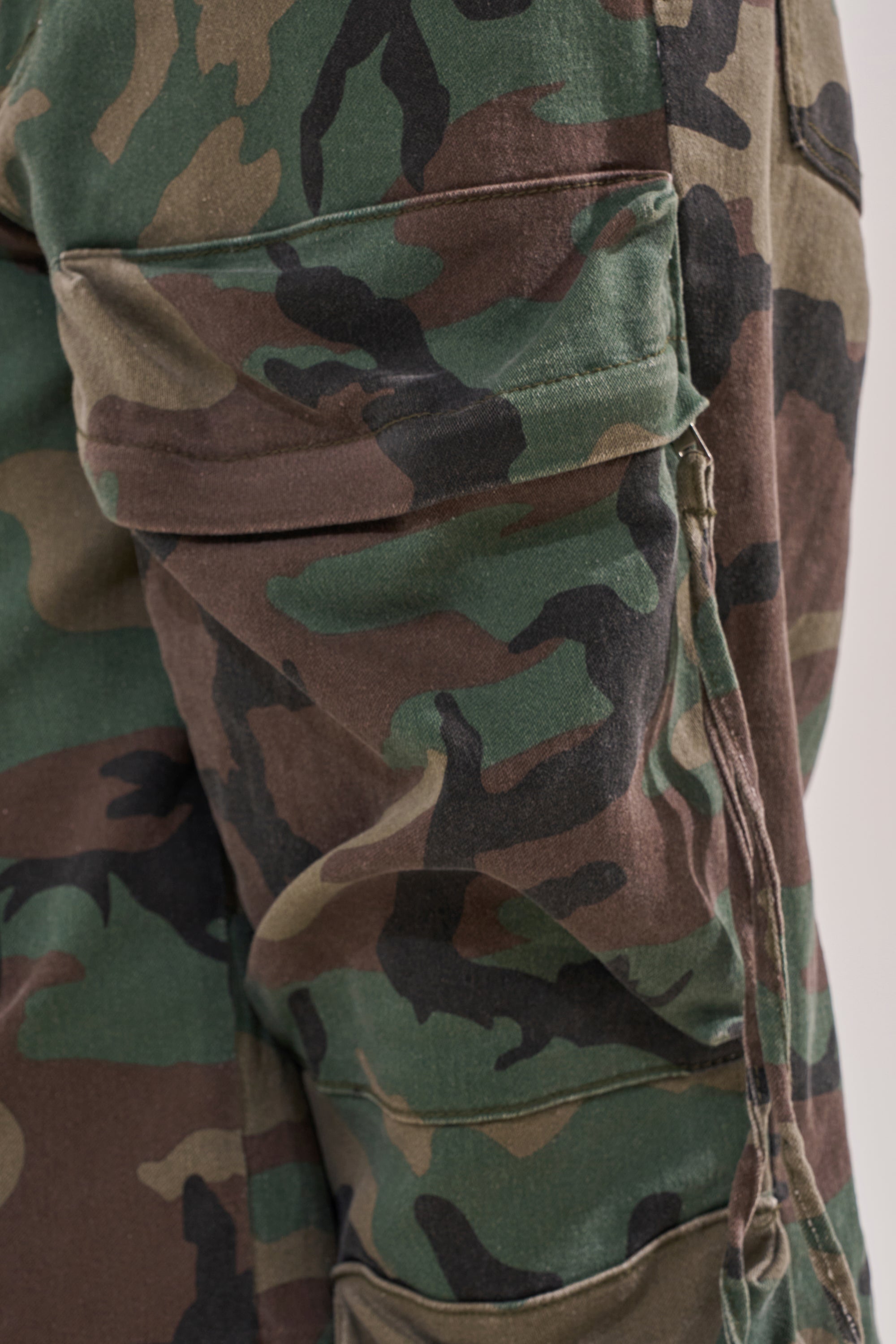 Close-up of the TAKE ME DOWN CAMO CARGO PANT, showcasing the side pocket and distinctive green, brown, and black camouflage on these wide-leg cargo pants. 7