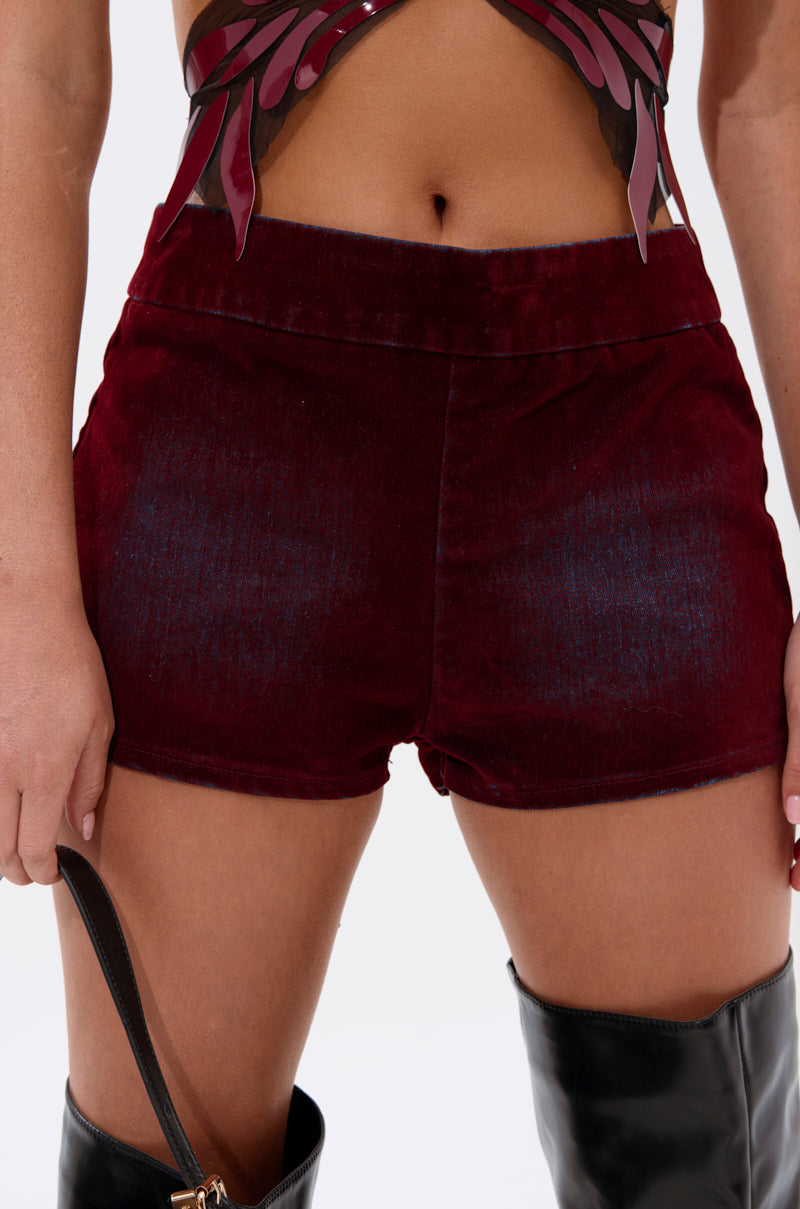 Wearing THE BEST VELVET DENIM HOT SHORT in deep red, paired with a maroon and black crop top and black thigh-high boots. Only the lower torso and upper legs are visible; one hand holds a black bag. 1