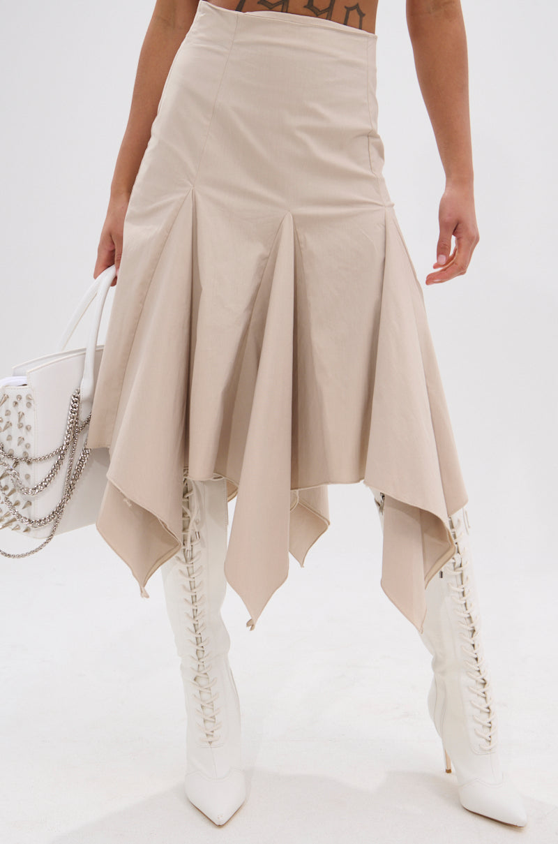 Someone is wearing the HANNAH MIDI SKIRT with handkerchief pleats, tall white lace-up boots, and a white handbag with chain and stud accents. The background is plain white. 1