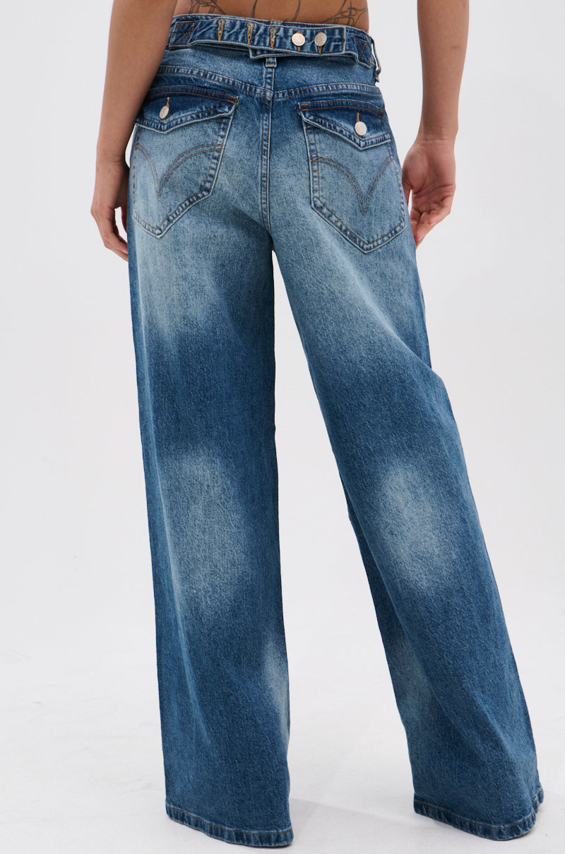 Wearing EXTREME RELAXED DENIM, featuring a high waist, ultra-wide leg, and double waistband, a person stands with their back to the camera against a plain white background.