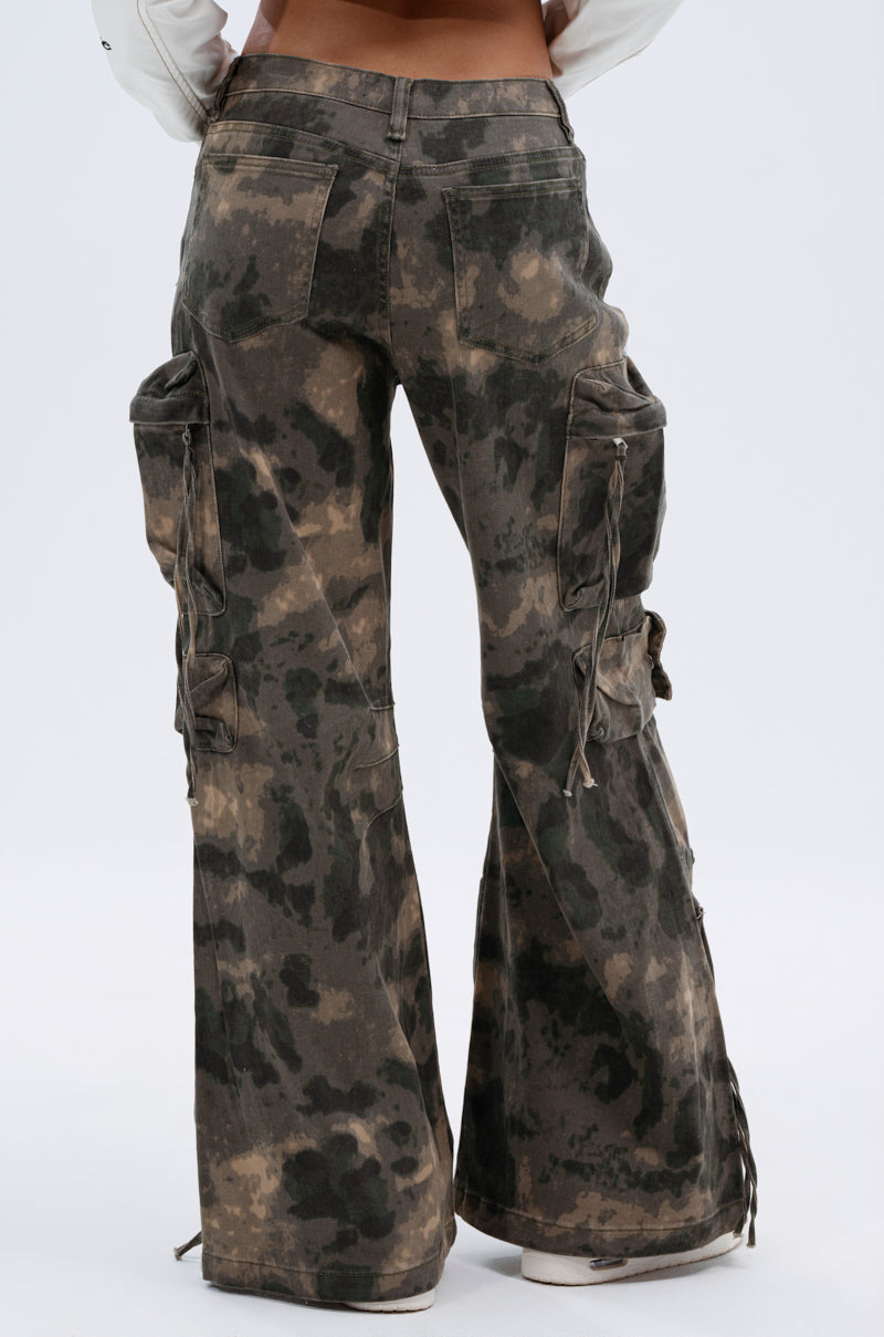 A person wearing the DOWN AND DIRTY CARGO PANT—high-rise, relaxed fit, camouflage cargo pants with side pockets and drawstring details—viewed from behind against a plain white background. 5