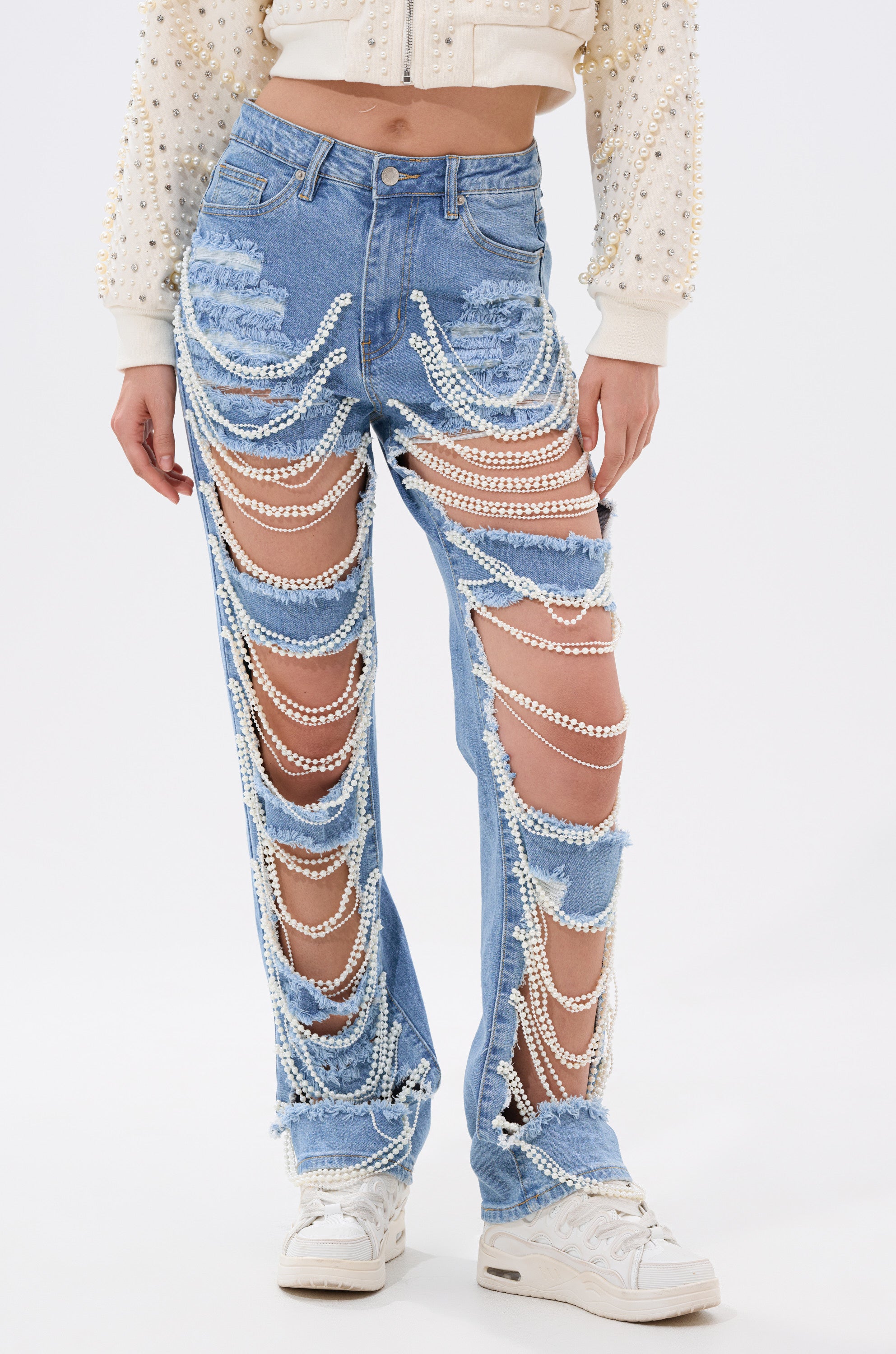 Someone styled in the DISTRESSED LIFE DENIM PANT, enhanced with chic faux pearl chain accessories.