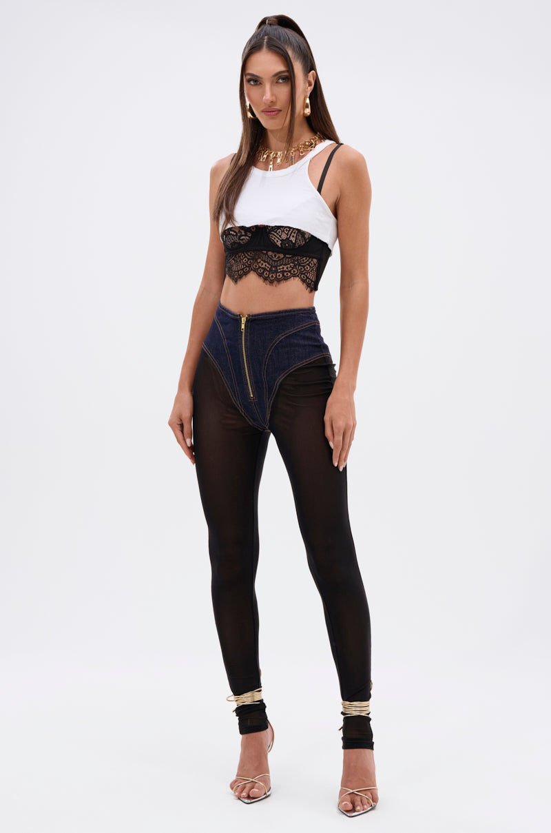 A woman poses against a plain background in the ZIP ME UP MESH LEGGING WITH DENIM PANTY, paired with a white crop top, gold anklets, and strappy heeled sandals for an edgy streetwear vibe. 7