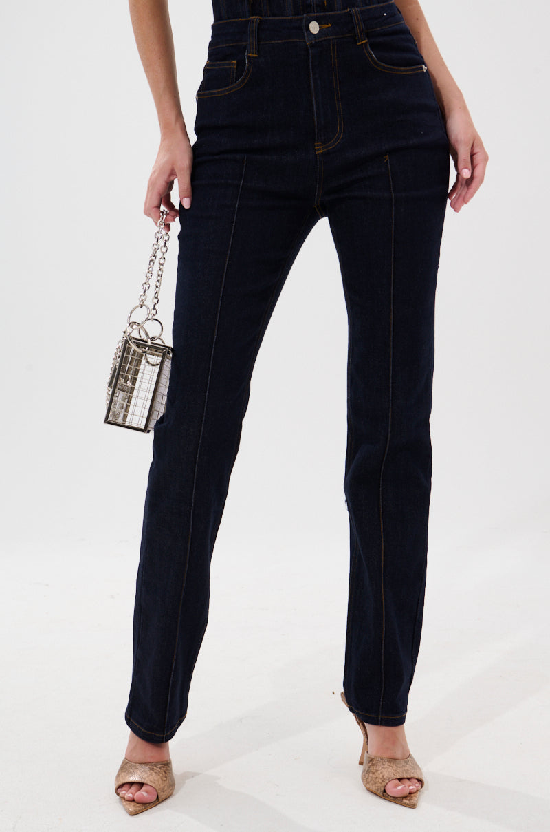 A person wearing GIVE IT TO ME BABY SKINNY DENIM jeans and open-toe heels holds a small silver box purse with a chain strap against a plain white background. 1