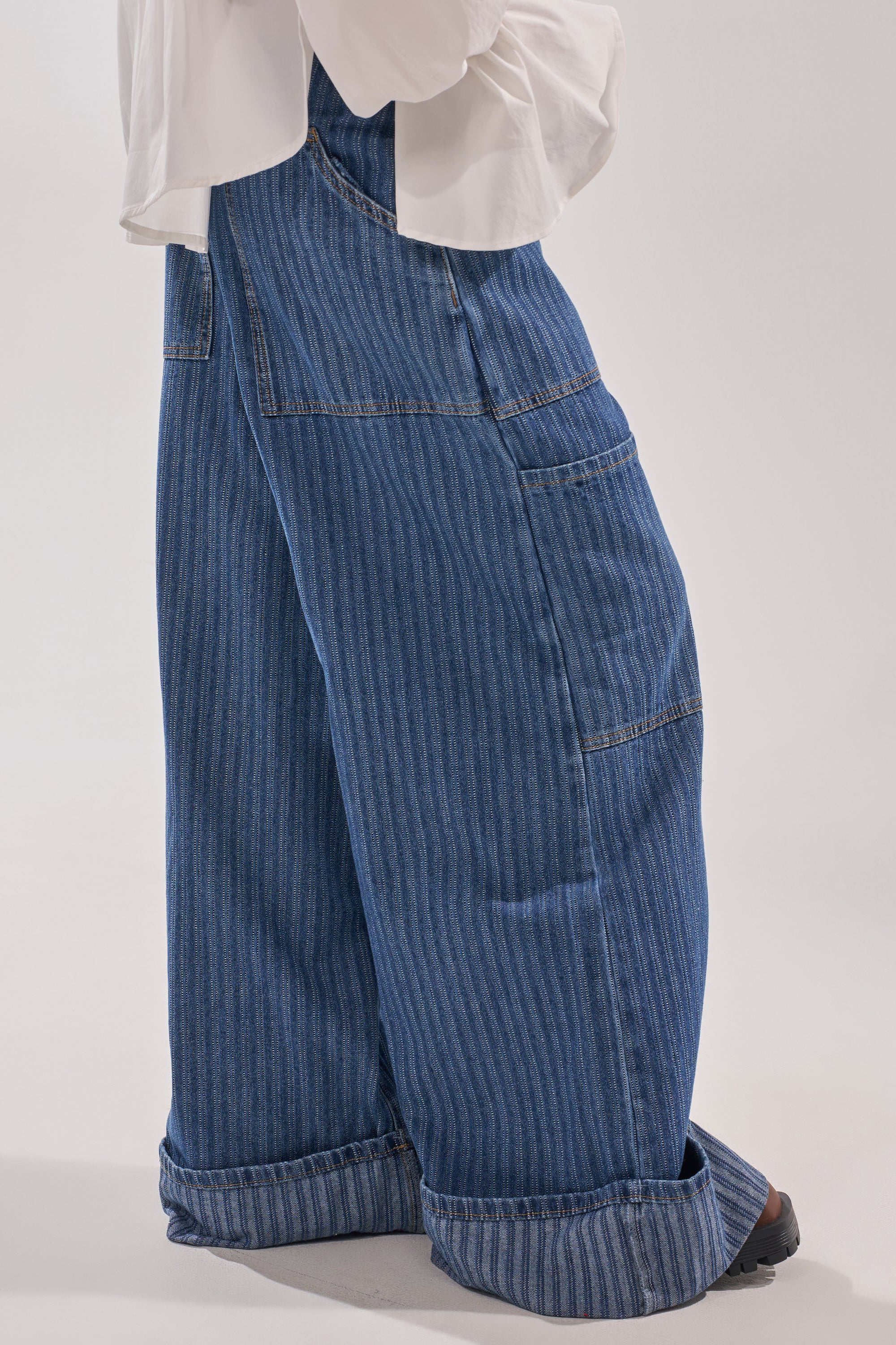 A person wears the BE MINE STRIPE DENIM wide-leg pants with subtle vertical stripes and a white long-sleeve shirt, standing against a plain light background. 4
