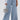Wearing the SUMMERTIME BLUES STRIPE WIDE LEG DENIM and a white long-sleeve top, a person holds a small silver birdcage purse. Only their lower half is visible.