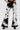 Wearing LETS GO TO THE RODEO BABY COW DENIM high-rise flare jeans with black pointed-toe heels, hands in pockets, against a plain white background for a modern take on western-inspired style.