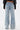 A person is seen from the back wearing WHO KNOWS DISTRESSED WIDE LEG DENIM: vintage-inspired, high-waisted jeans with exposed seams, frayed edges, vertical panels, and patch pockets.