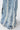 Close-up of the WHO KNOWS DISTRESSED WIDE LEG DENIM: vintage-inspired light blue jeans with vertical frayed seams, distressed edges, visible stitching, and a wide-leg fit, set against a light background.