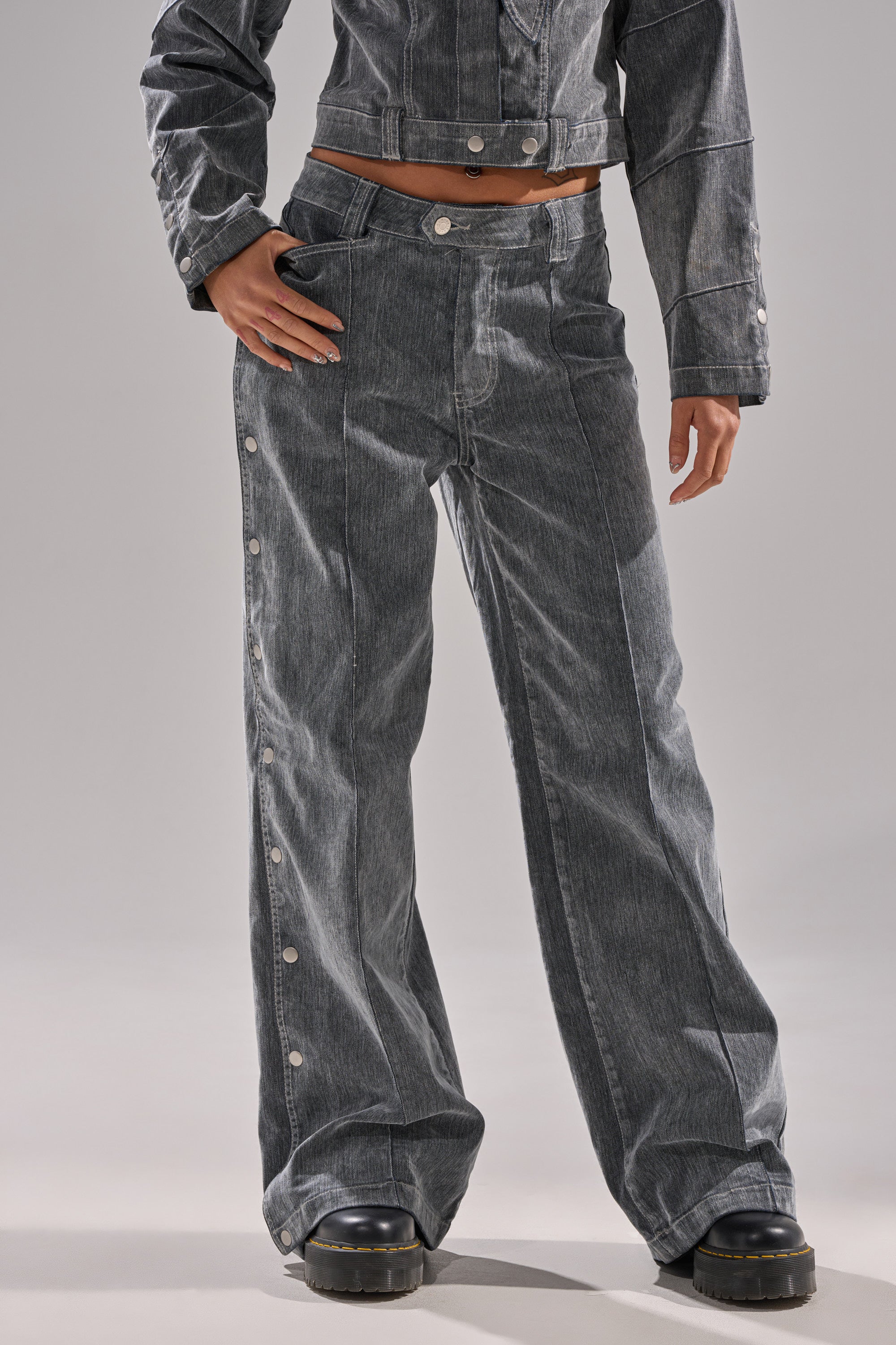 Wearing CATCHING EYES VELVET DENIM WIDE-LEG PANT in gray with snap buttons on the sides, paired with black chunky platform shoes and a cropped matching jacket; only the lower half of the body is shown.