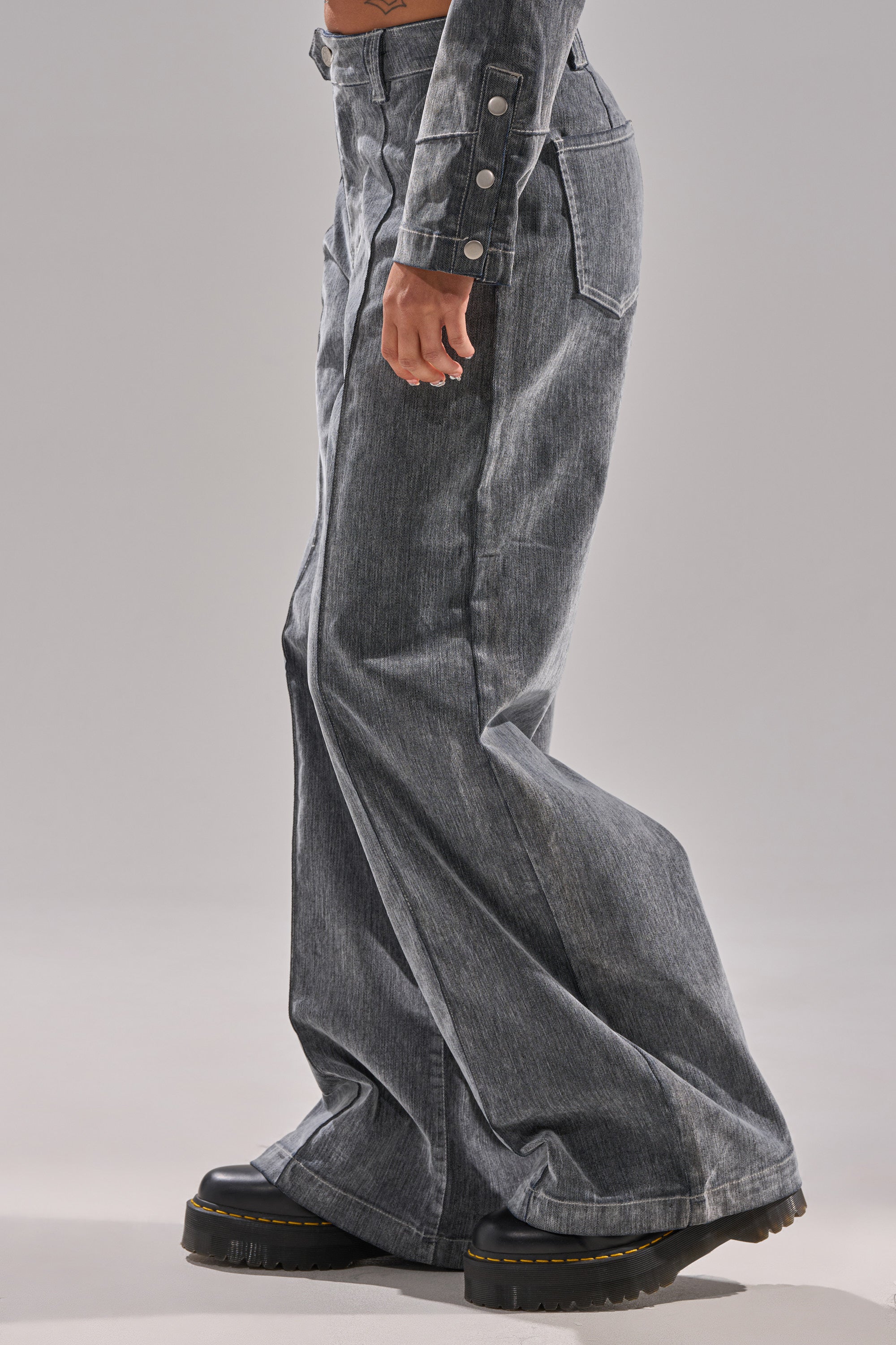 Wearing the CATCHING EYES VELVET DENIM WIDE-LEG PANT and a matching gray denim jacket with buttons, paired with black platform shoes, a person stands against a plain light background.